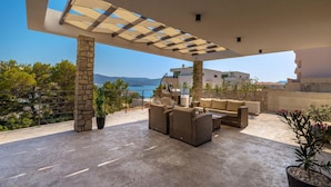 A covered outdoor seating area with wicker furniture, stone pillars, and a view of the sea. - Lovely home in Slivno with WiFi (Slivno)