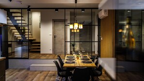 A modern dining area with a wooden table set for four, black chairs, and pendant lighting. - Lovely home in Slivno with WiFi (Slivno)