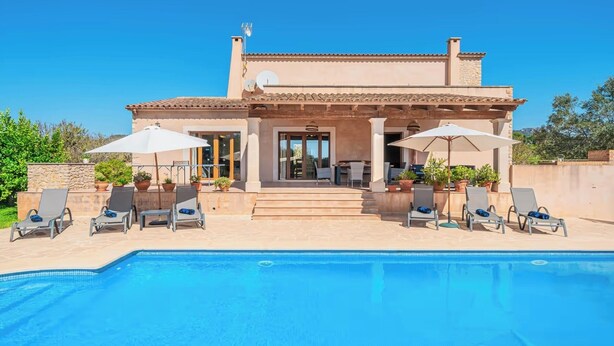 Une villa moderne dotée d’une piscine, d’un espace salon extérieur et d’une façade en pierre.