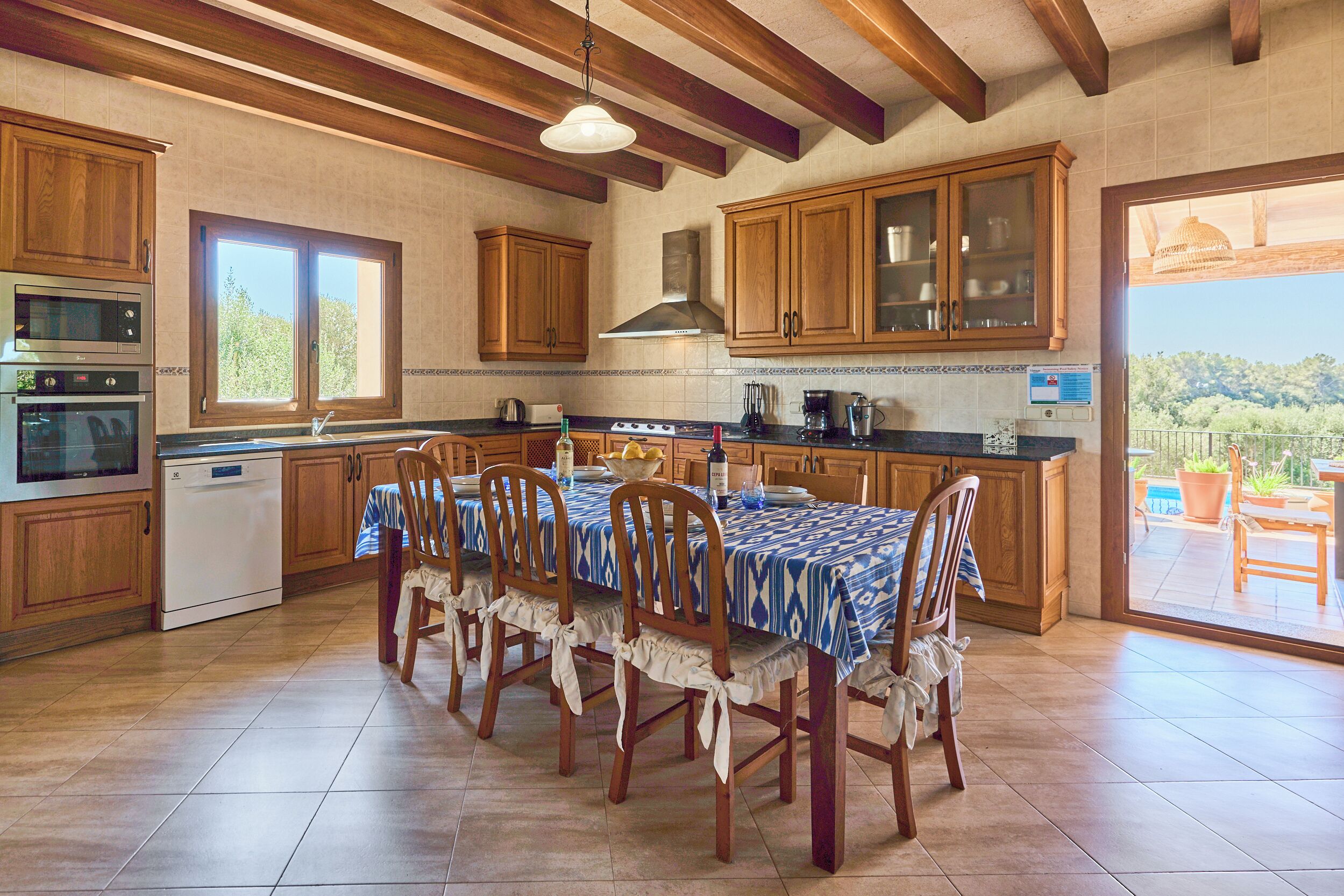 A kitchen with wooden cabinets, a dining table with chairs, and a view through a glass door to an outdoor patio.
