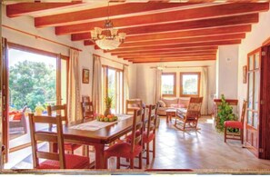 Enjoy meals in this airy dining area with a high ceiling and large windows offering views of the surrounding greenery.