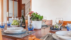 Une table à manger dressée avec des assiettes, des verres, une bouteille et une plante décorative.