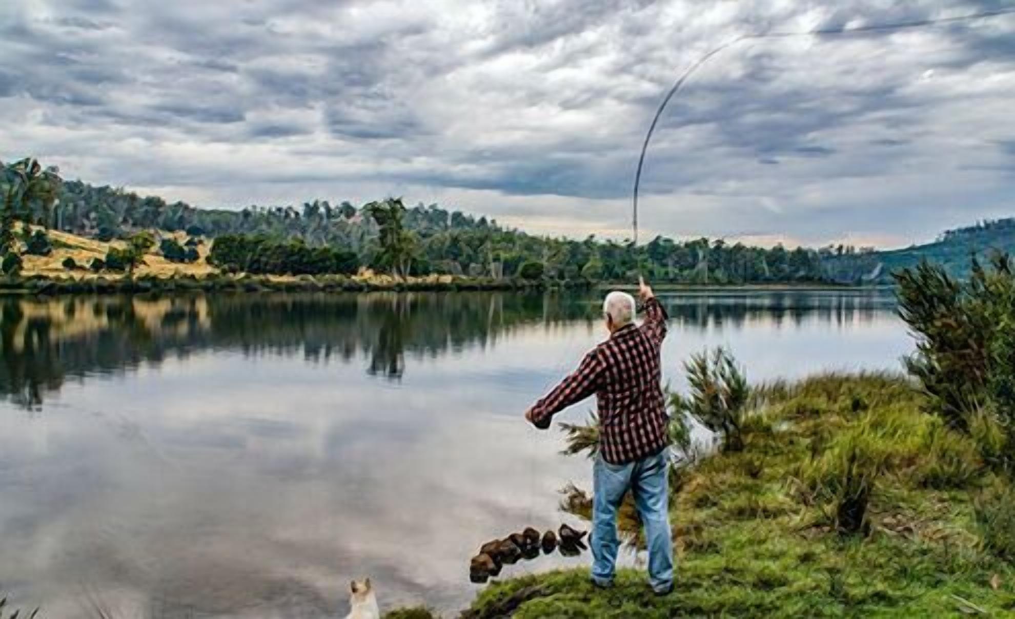 A person fishing by a calm lake with a clear sky.