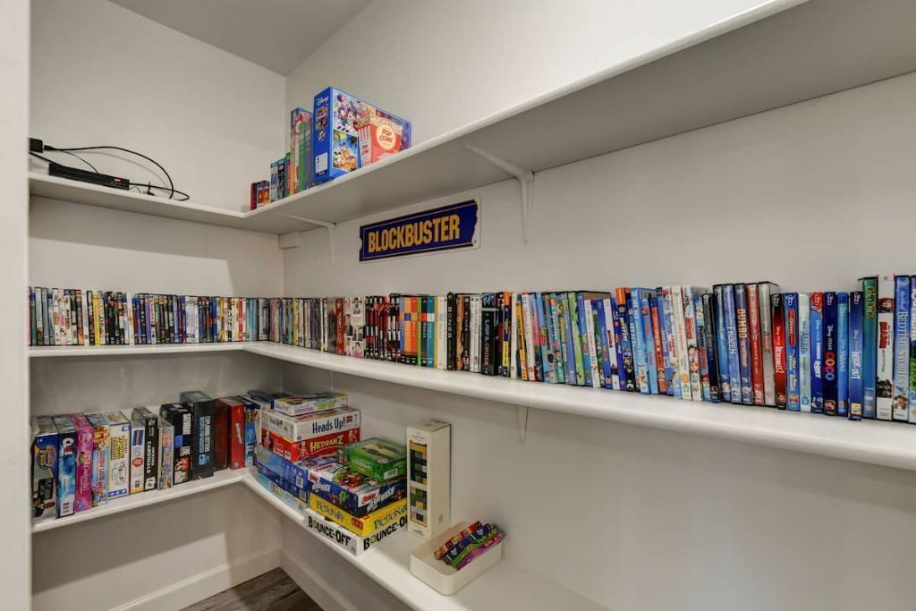 A room with white walls and shelves filled with books and DVDs.