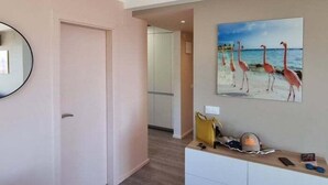 A hotel lobby with a painting of flamingos on the wall, a reception desk with a phone and a bag, and a door leading to another room. - Roses with sea views, Canyelles Brava beach, AV-10 (Rosas / Roses)
