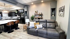 A modern kitchen with dark cabinets, a central island, and a dining area with bar stools. - Adorable 7 bedroom place (Mitchell)