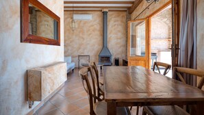 Een rustieke eethoek met een houten tafel en stoelen, een stenen openhaard en een groot raam.