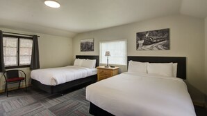 A hotel room with two beds, a chair, a nightstand, and a window with curtains.