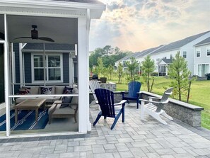 A covered patio with outdoor furniture, a ceiling fan, and a view of a residential neighborhood. - Bayside * 5BR Luxury Home (Selbyville)
