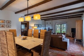 Un espace repas avec une table en marbre, des chaises en osier et des luminaires suspendus.