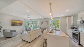 A modern kitchen with a central island, a dining area with a sofa, and a view of the outdoors.
