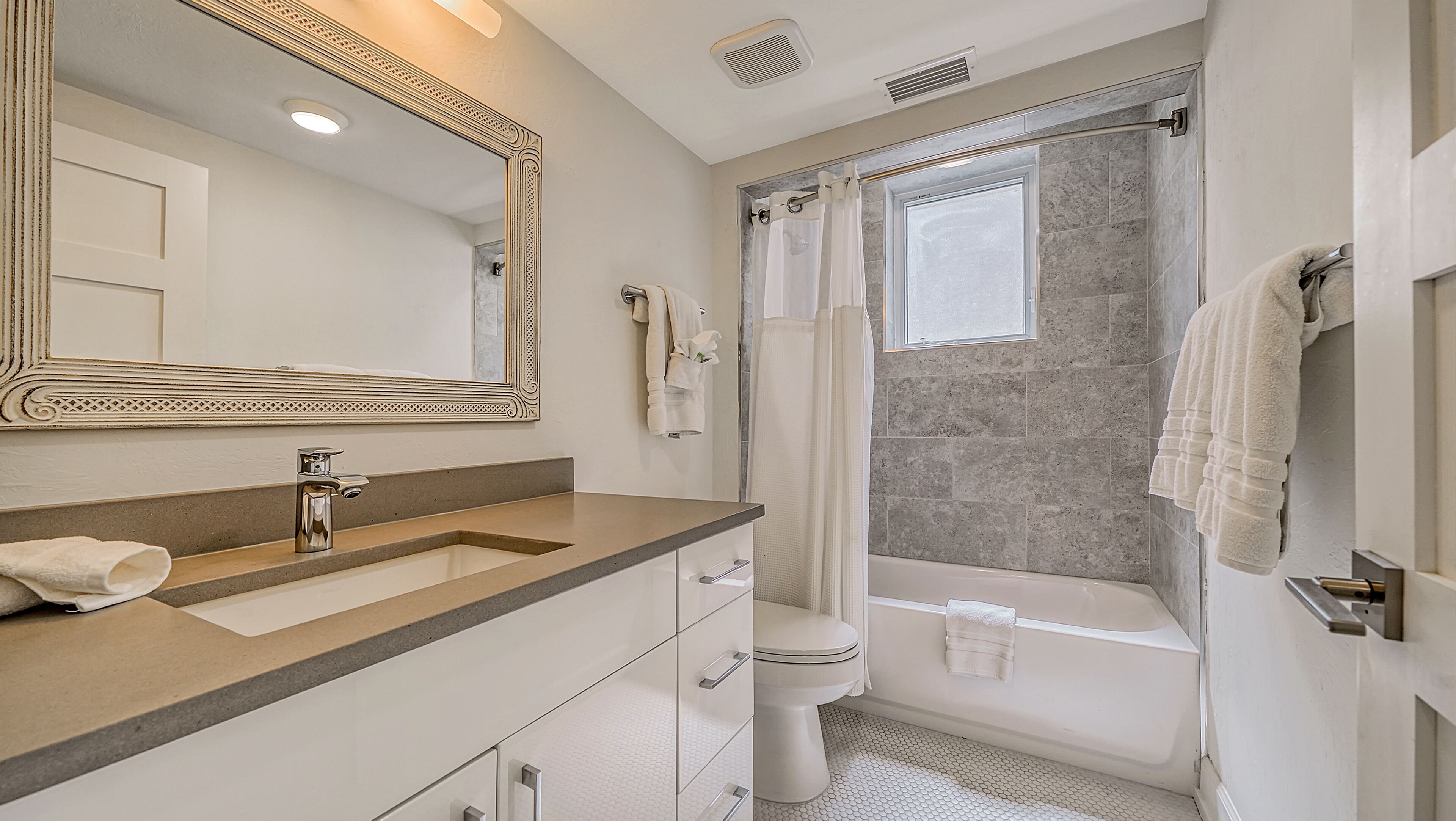 Une salle de bain avec un grand miroir, un lavabo, des toilettes et une baignoire.