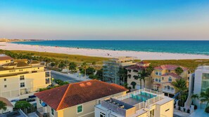 A coastal hotel with a rooftop pool, beach view, and multiple buildings with balconies.