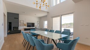 A modern dining area with a glass table and blue chairs, a TV, and a fireplace. - Cozy home in Grubine with sauna (Grubine)