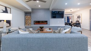 A modern living room with a grey sofa, a wooden coffee table, and a fireplace.