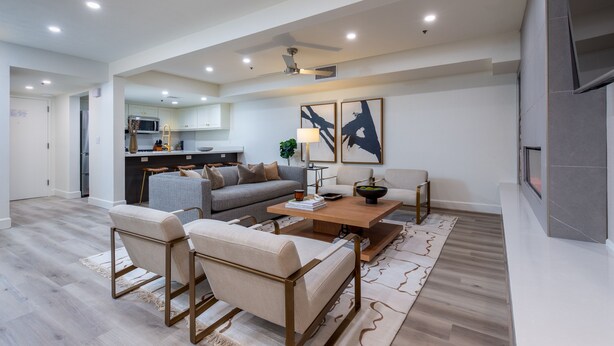 A modern living room with a sofa, chairs, a coffee table, and artwork on the wall.