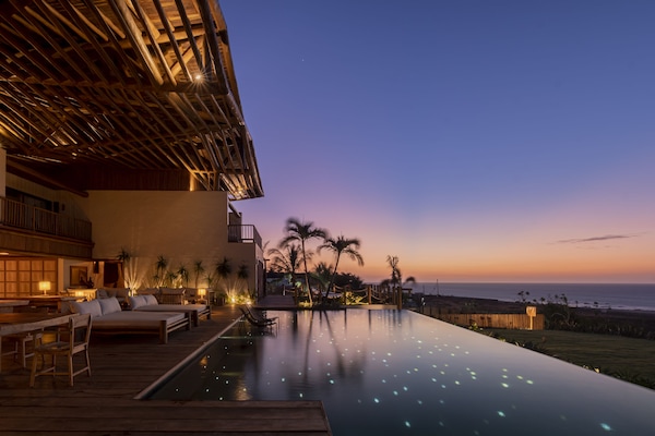 Una piscina al aire libre, sombrillas, sillones reclinables de piscina