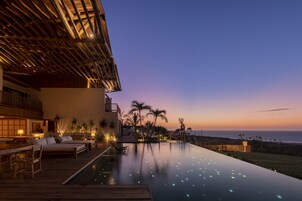 Una piscina al aire libre, sombrillas, sillones reclinables de piscina