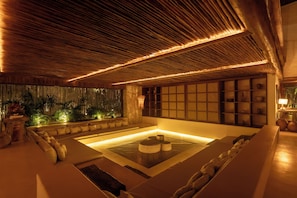 Área de spa com banheira de pedra aquecida, assentos e vista para o exterior.