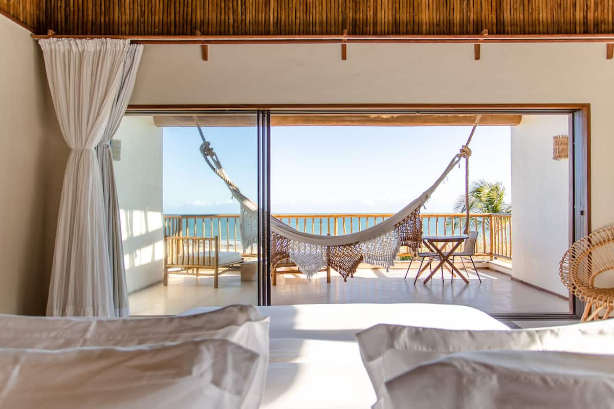 Una habitación con cama, una hamaca y un balcón con vistas al mar.