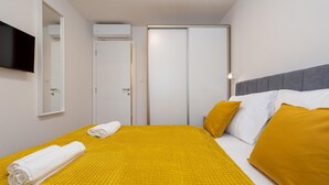 Una camera d'albergo con un letto, una televisione a parete e un armadio.