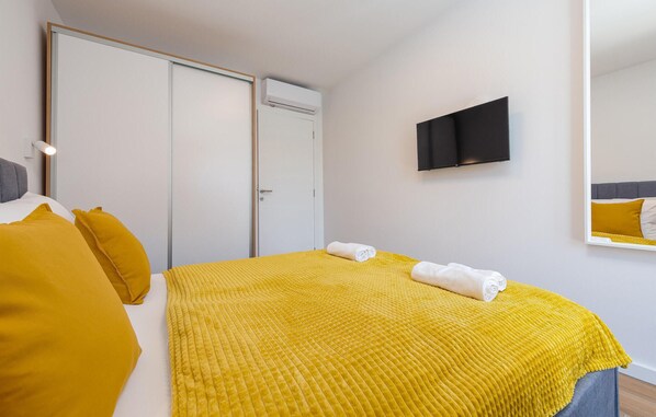 A hotel room with a bed, a wardrobe, a television, and a mirror.