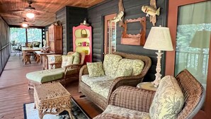 A wooden deck with wicker furniture, a ceiling fan, and a dining area.