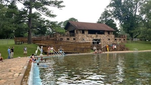 A rustic stone building with a wooden deck and a swimming pool.