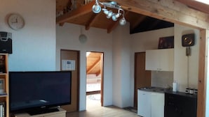 A spacious kitchen with wooden cabinets, a built-in dishwasher, and a large flat-screen TV.
