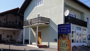 A two-story building with a balcony, a satellite dish, and a signboard advertising 'OPG Balja'.