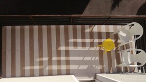 A room with a striped wall, a white floor, and a yellow chair.