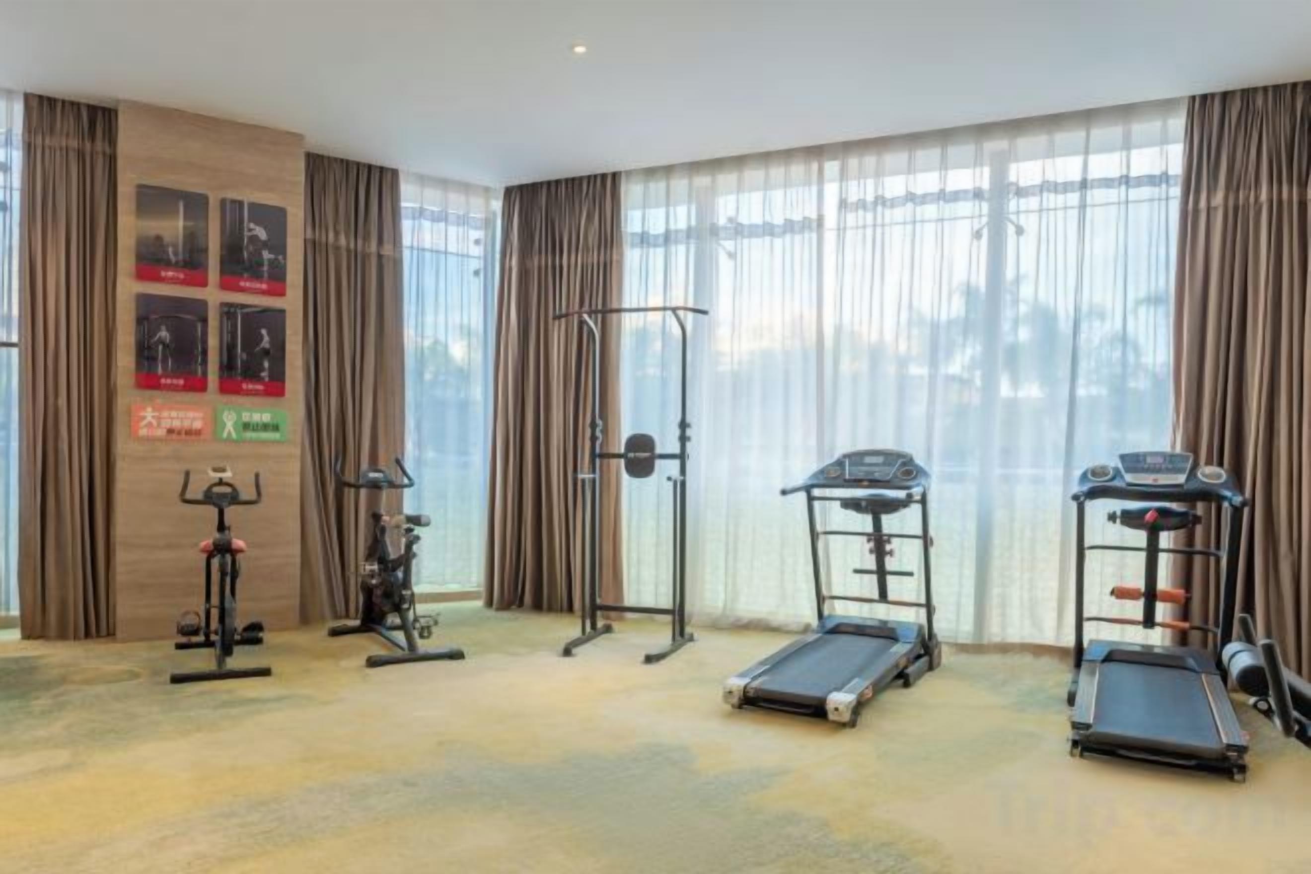 A hotel room with a gym area featuring cardio equipment, a pull-up bar, and a treadmill.