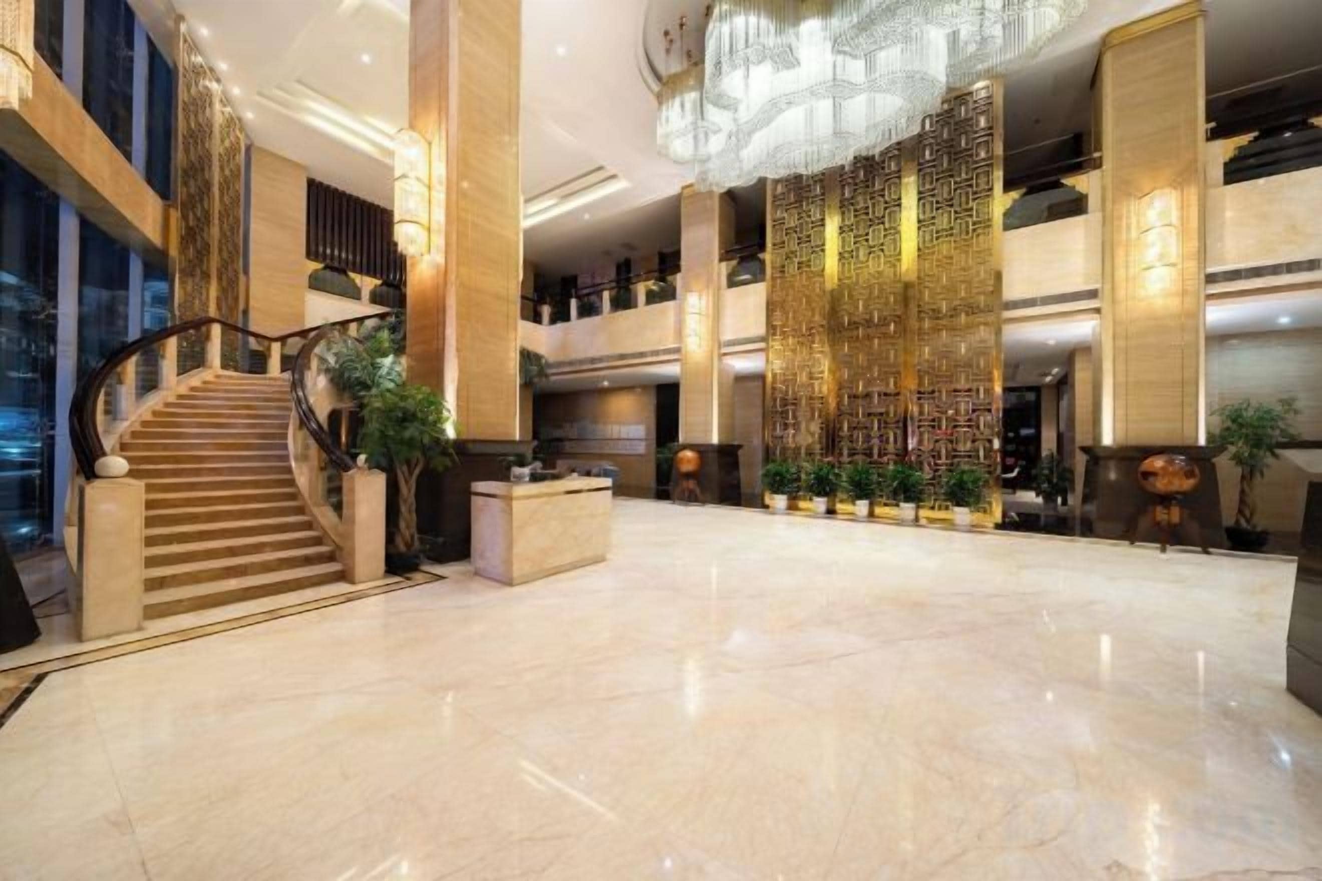 A spacious lobby with a grand staircase, a reception desk, and a decorative wall.