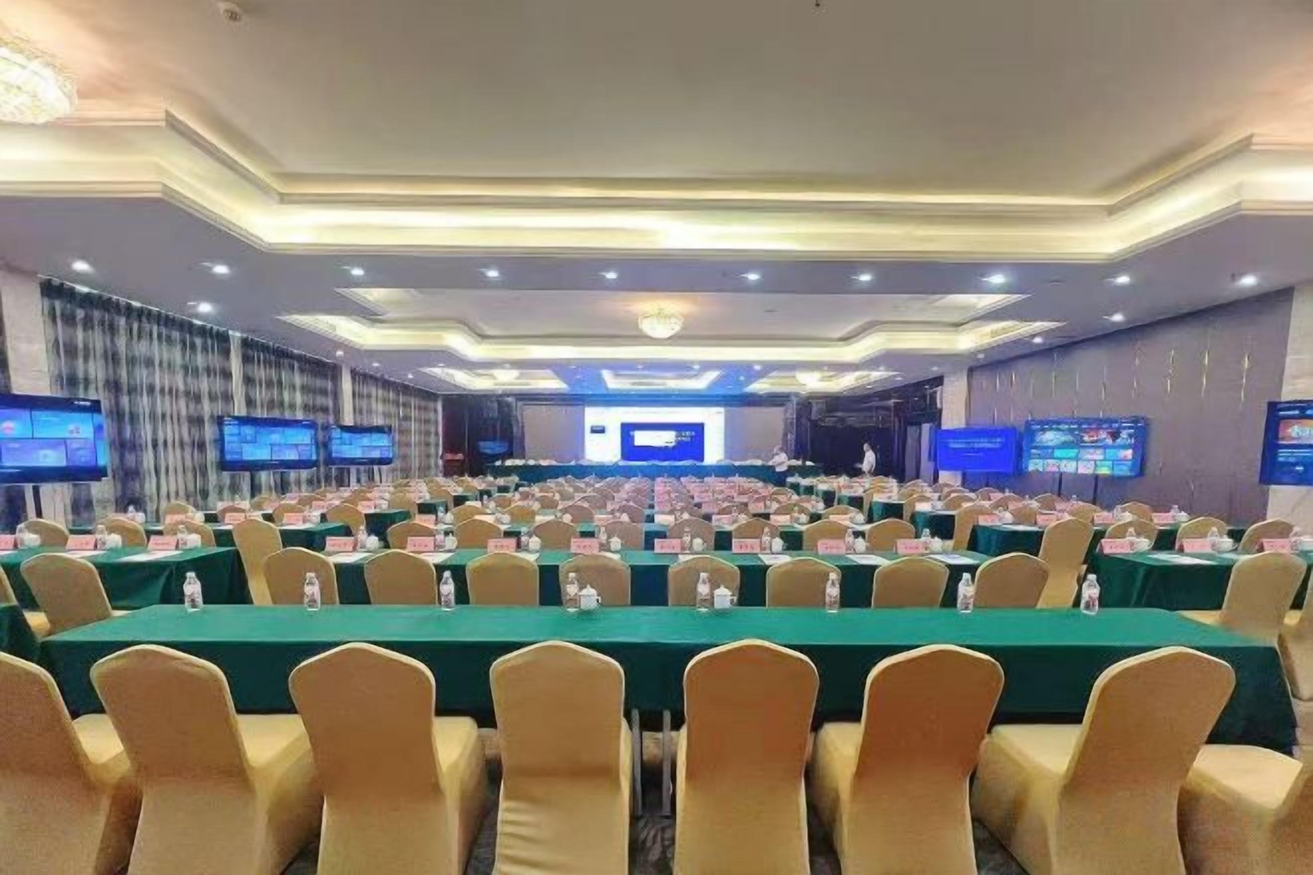 Un salón de conferencias con filas de mesas y sillas, equipado con botellas de agua y tarjetas de identificación.