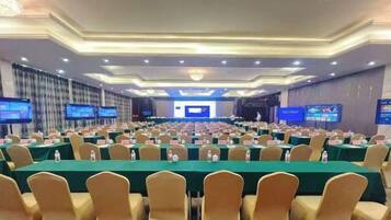 Un salón de conferencias con filas de mesas y sillas, equipado con botellas de agua y tarjetas de identificación.