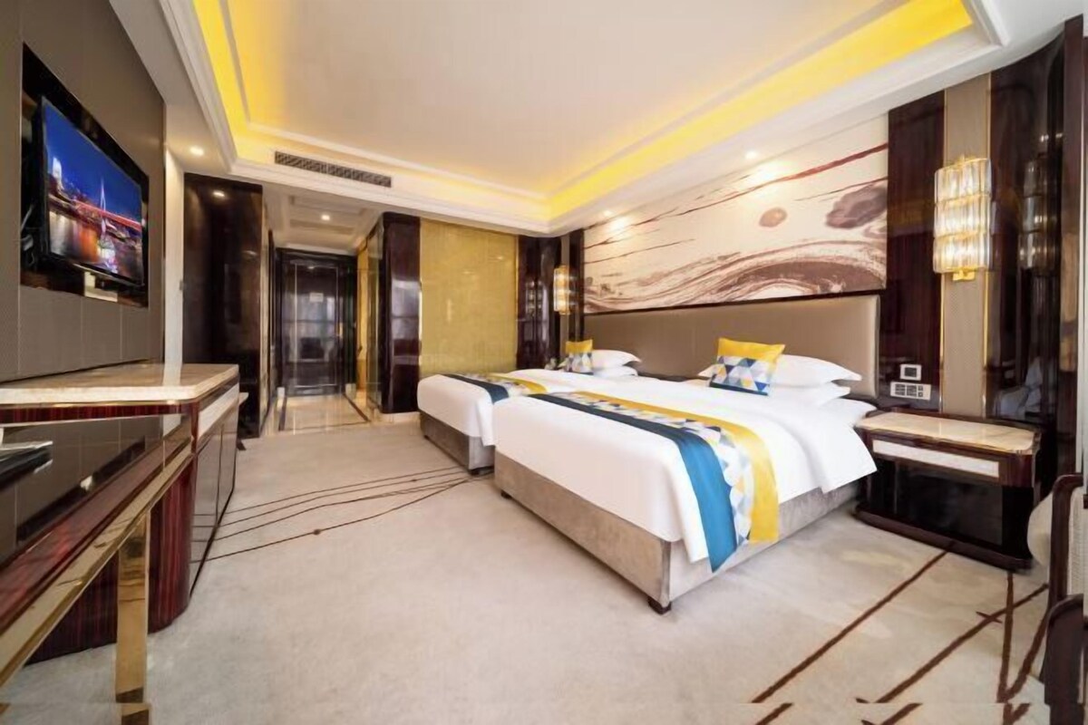 A modern hotel room with a large bed, a TV, and a desk.
