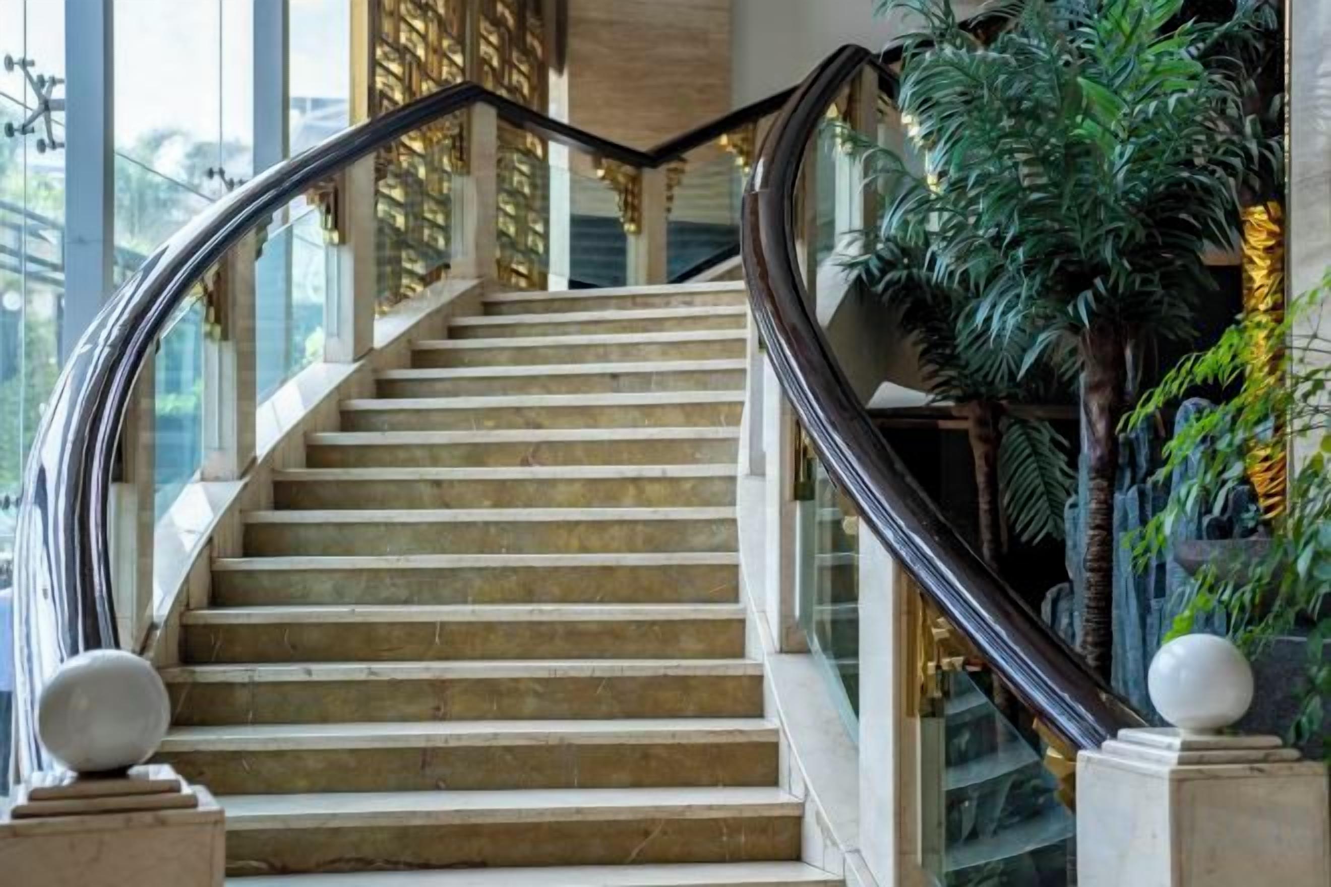 A marble staircase with a glass railing, leading to a higher floor.
