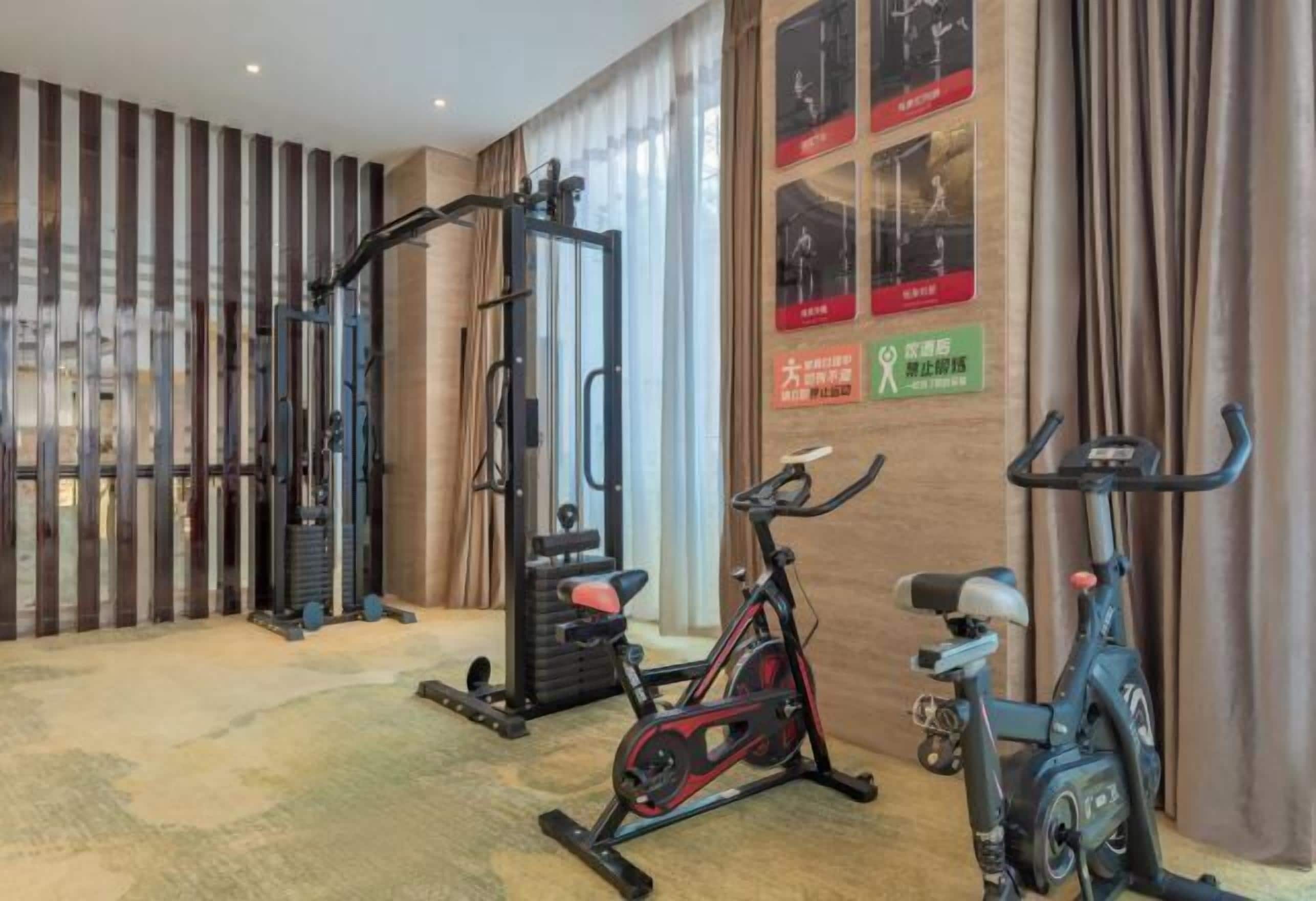 Un gimnasio con equipo de ejercicio, incluyendo una bicicleta estática, una cinta de correr y una máquina de pesas.