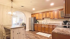 A modern kitchen with wooden cabinets, a stainless steel refrigerator, and a marble countertop. - Full Kitchen // Spacious Living Room // Walk to Mineral Springs and Restaurants (Hot Springs)