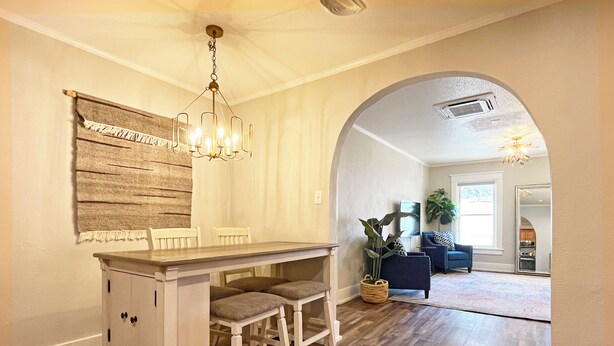A dining area with a wooden table and chairs, a chandelier, and a large mirror. - Full Kitchen // Spacious Living Room // Walk to Mineral Springs and Restaurants (Hot Springs)
