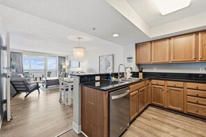 A modern kitchen with wooden cabinets, a black countertop, and a built-in dishwasher.