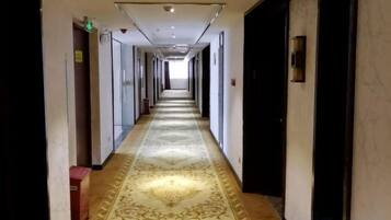 Un pasillo de hotel con piso alfombrado, puertas a ambos lados e iluminación empotrada en el techo.