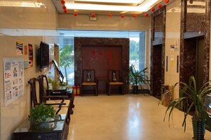 Un hall d’hôtel comprenant un comptoir d’accueil, un espace salon et une grande fenêtre.