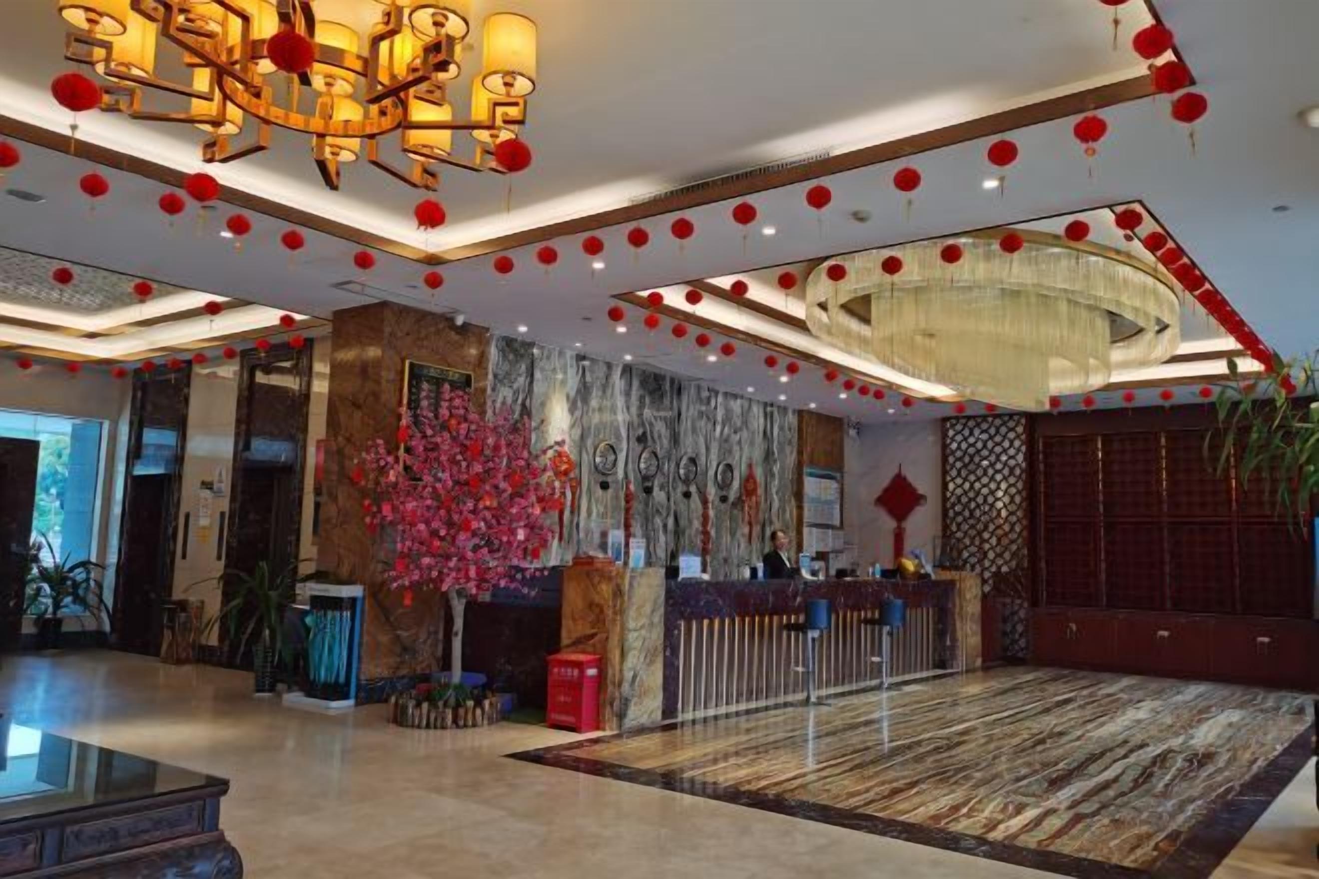 Un vestíbulo de hotel con una recepción, una araña y una alfombra estampada.