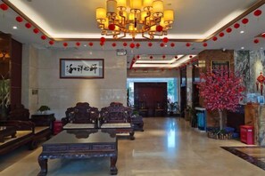 A lobby with a reception desk, seating area, and a chandelier. - Zhao He Hotel (Nanning)