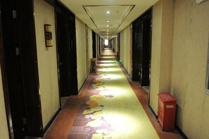 A hotel hallway with carpeted floors, doors on both sides, and a trash bin on the right. - Zhao He Hotel (Nanning)