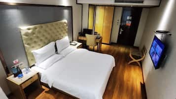 Una habitación de hotel con una cama grande, un escritorio, una silla, un televisor y un armario.