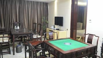 Una habitación con mesa de billar, sillas de madera, televisor y un espejo grande.