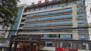 Een meerhoog hotelgebouw met een modern gevelontwerp, met grote ramen en een opvallend bord met de tekst ZHAO HE HOTEL.