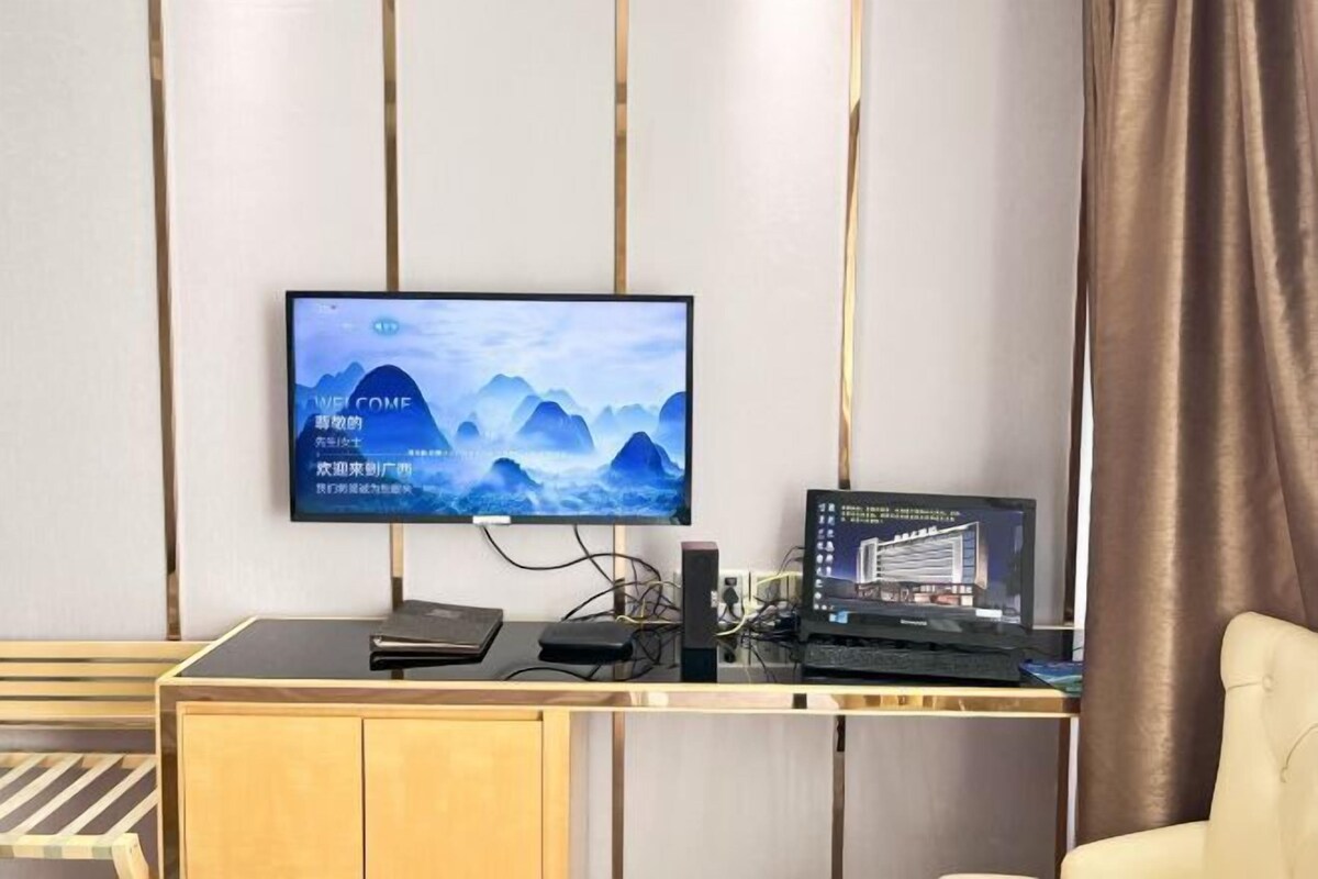 A modern office desk with a computer monitor displaying a scenic wallpaper, a laptop, and a keyboard.